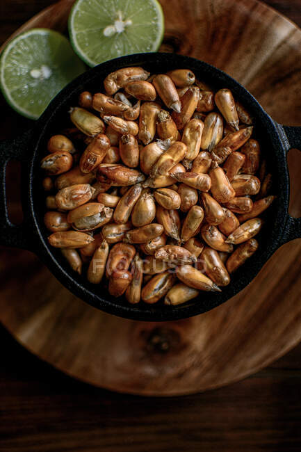 Vista dall'alto di mucchio di grano di cereali in ciotola e calce posto sul tavolo di legno in cucina — Foto stock
