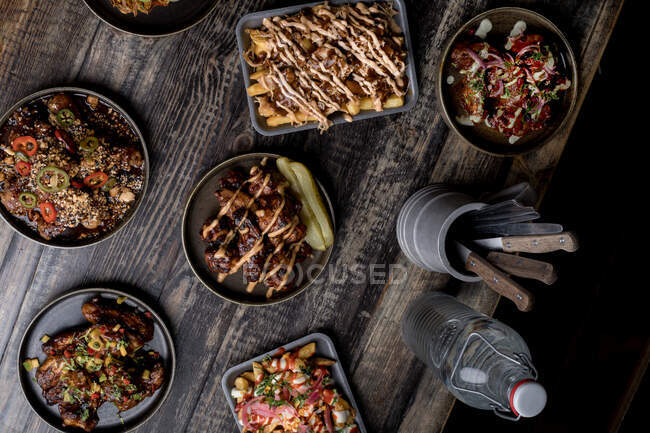 Mesa de madeira servida com hambúrgueres apetitosos e asas de frango no restaurante de comida de rua — Fotografia de Stock