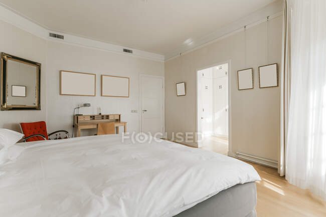 Cómoda cama y mesitas de noche de madera colocadas en un amplio dormitorio en un apartamento moderno - foto de stock