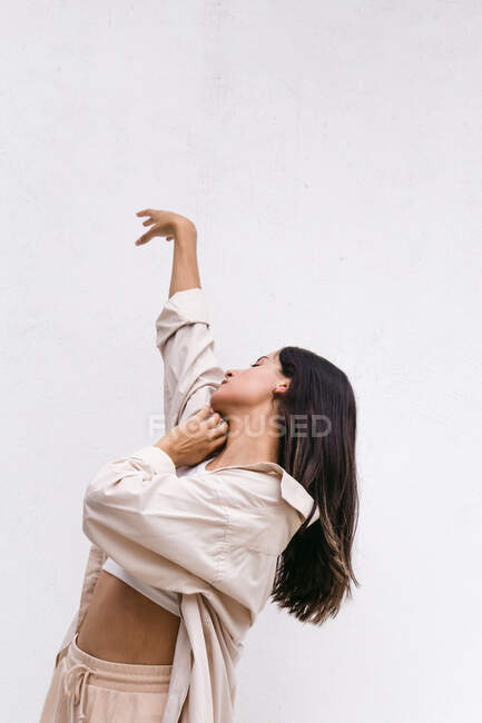 Talented contemporary female dancer moving and dancing near white wall in urban area in city — Stock Photo