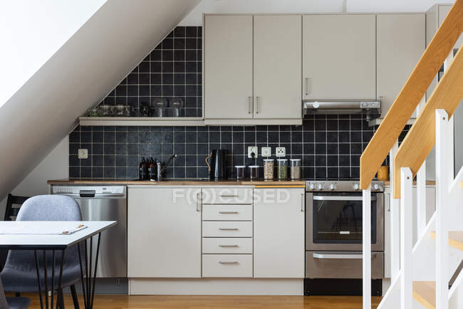 Інтер'єр сучасної кухні з білими меблями і чорною плиткою на стіні, спроектований в мінімальному стилі в будинку — стокове фото