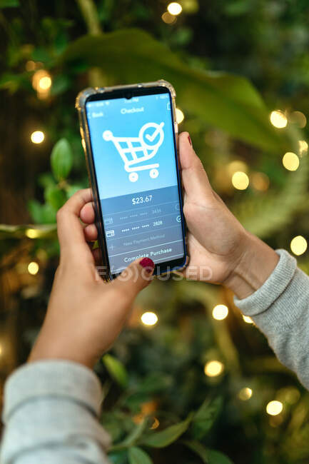Crop anonymous female using application for online shopping on mobile phone and making payment for order — Stock Photo
