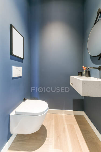 Стильный интерьер ванной комнаты с белой керамической раковиной и настенным туалетом в минимальном стиле — стоковое фото