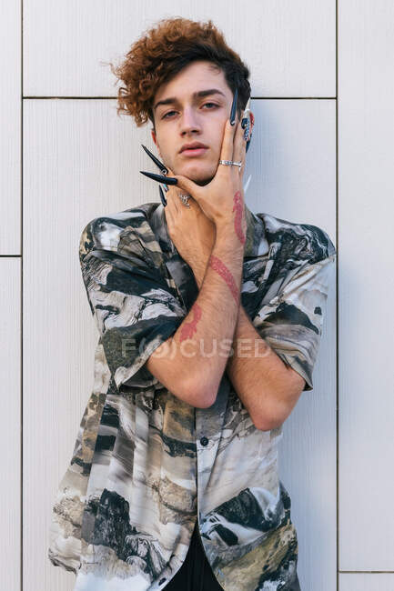 Homem vaidoso jovem em desgaste elegante com unhas longas em pé na parede de azulejos olhando para a câmera — Fotografia de Stock