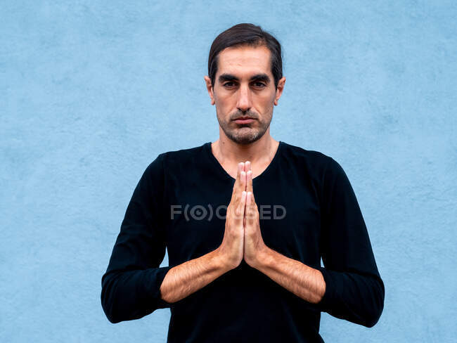 Heiterer ethnischer Mann steht in Gebetshänden auf der Straße und praktiziert Yoga — Stockfoto