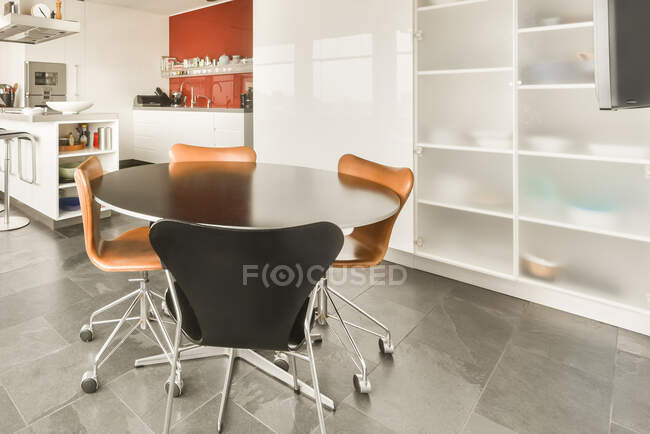 Круглий стіл і стільці розміщені в сучасній просторій кімнаті поруч з кухнею — стокове фото