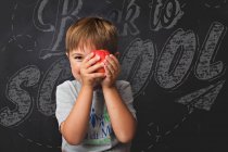 Petit garçon souriant tenant une pomme — Photo de stock