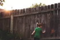 Little boy drawing on wooden fence — Stock Photo