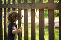 Little boy looking through wooden fence — Stock Photo