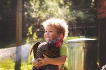 Menino abraçando galinha grande — Fotografia de Stock