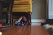 Little boy hiding under armchair — Stock Photo