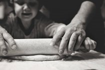 Little boy rolling dough with grandmother — Stock Photo