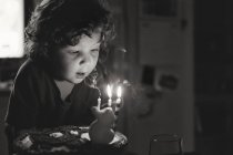 Chico soplando velas en pastel de cumpleaños - foto de stock