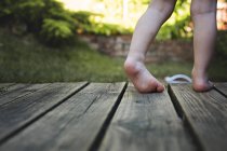Ноги маленького хлопчика на дерев'яній підлозі — стокове фото