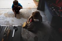 Kleine Brüder kehren Fußboden in Werkstatt — Stockfoto