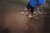Petit garçon debout sur du sable mouillé — Photo de stock