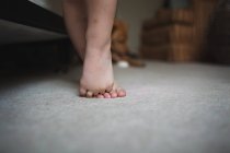 Piedi di bambino in piedi su tappeto — Foto stock