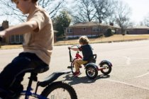Hermanos pequeños en bicicletas en bicicleta por carretera - foto de stock