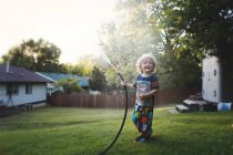 Маленький хлопчик грає з садовим шлангом — стокове фото