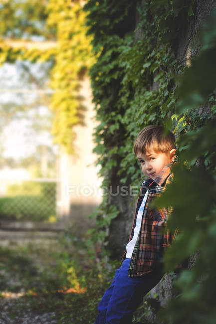 Petit garçon appuyé sur un vieux mur de pierre — Photo de stock
