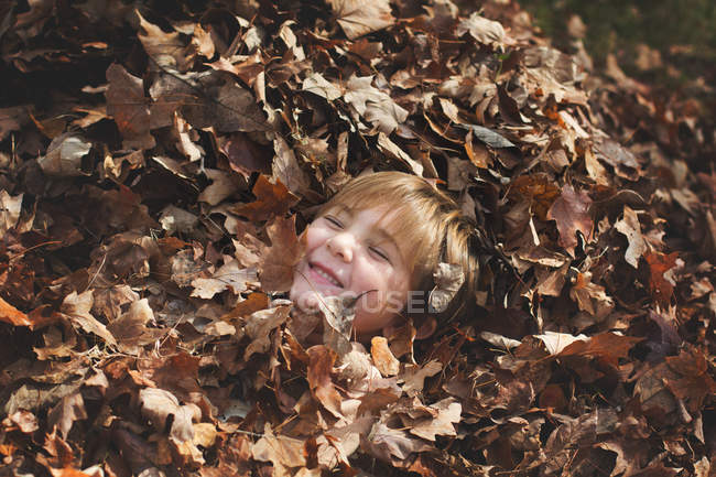 Petit garçon jouer dans automne feuilles — Photo de stock