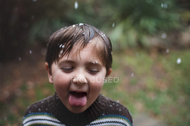 Little boy catching snowflakes with tongue — Stock Photo