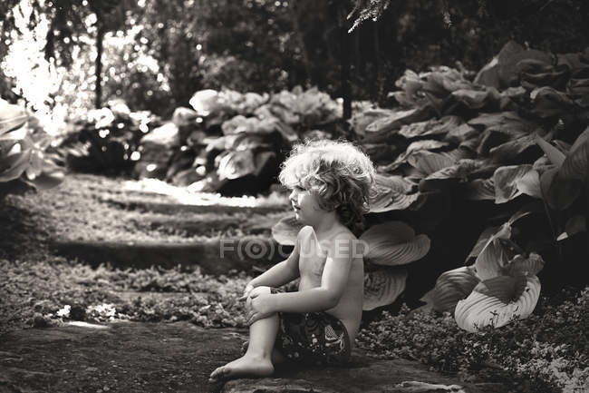 Entzückender kleiner Junge sitzt im Garten — Stockfoto