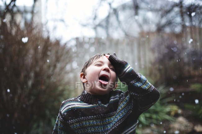 Маленький хлопчик ловить сніжинки язиком — стокове фото