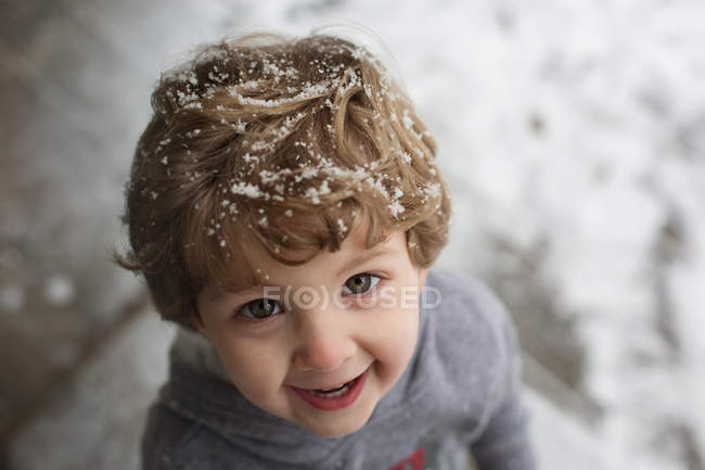 Усміхнений маленький хлопчик зі снігом у волоссі — стокове фото