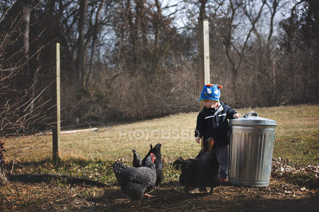 Beau petit garçon nourrissant les poules — Photo de stock