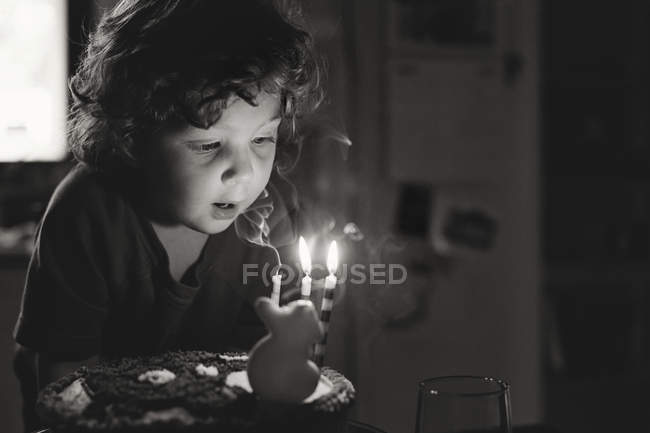 Garçon soufflant des bougies sur gâteau d'anniversaire — Photo de stock