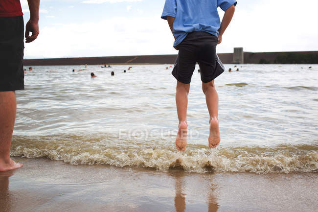 Хлопчик стрибає у воду на пляжі — стокове фото