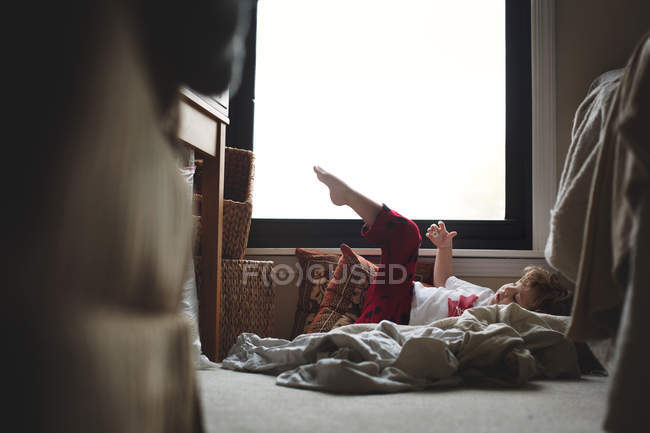Niño tendido sobre almohadas - foto de stock