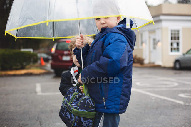 Два мальчика стоят под зонтиком — стоковое фото
