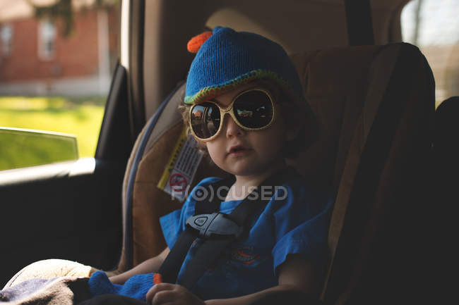 Garçon assis dans une voiture dans une chaise de sécurité — Photo de stock