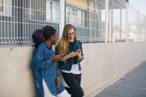 Mujeres jóvenes que utilizan teléfonos inteligentes en la calle, se centran en primer plano - foto de stock