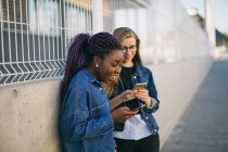 Junge Frauen, die auf der Straße Smartphones benutzen, konzentrieren sich auf den Vordergrund — Stockfoto