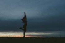 Silhouette de femme contre le ciel bleu au coucher du soleil, mise au point sélective — Photo de stock