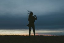 Silhouette de femme contre le ciel bleu au coucher du soleil, mise au point sélective — Photo de stock