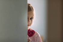 Mädchen isst bunten Lutscher zu Hause, selektiver Fokus — Stockfoto