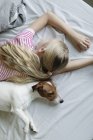 Vista elevada da menina com cão bonito na cama — Fotografia de Stock