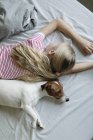 Вид девочки с симпатичной собакой на кровати — стоковое фото