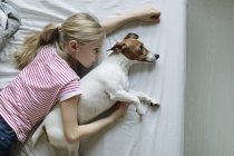 Vista elevata della ragazza con cane carino sul letto — Foto stock