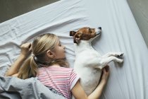 Vista elevada da menina com cão bonito na cama — Fotografia de Stock