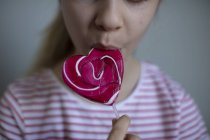Vista cortada de menina comendo pirulito rosa, foco seletivo — Fotografia de Stock
