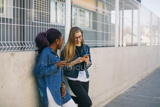 Junge Frauen, die auf der Straße Smartphones benutzen, konzentrieren sich auf den Vordergrund — Stockfoto
