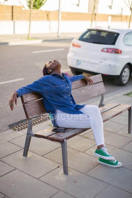 African woman sitting on city bench — Stock Photo