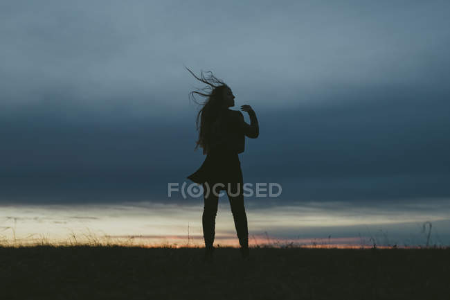 Silhouette di donna contro cielo blu al tramonto, messa a fuoco selettiva — Foto stock
