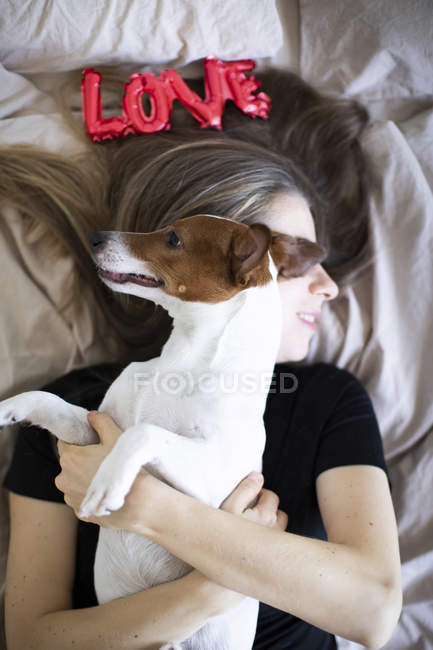 Молодая женщина с собакой с красными воздушными шарами в форме слова любовь, избирательный фокус — стоковое фото