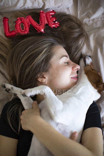 Mujer joven con perro con globos rojos en forma de palabra amor, enfoque selectivo - foto de stock